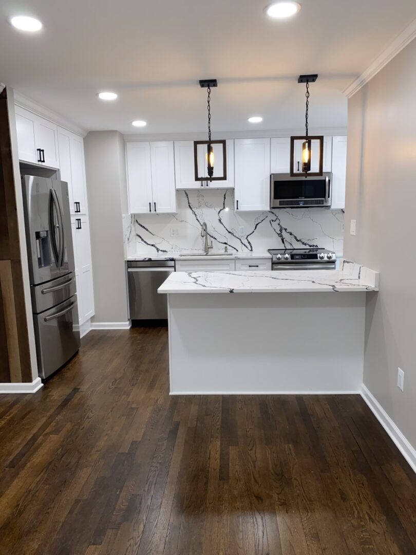 A kitchen with white cabinets and black marble counter tops.
